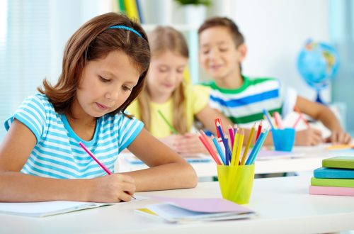 Portrait of serious girl drawing at workplace with her schoolmates on background